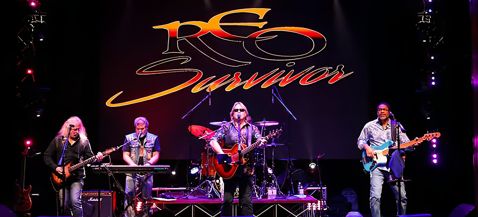 REO Survivor & Co. band on stage under the REO Survivor logo, a tribute to REO Speedwagon, Loverboy and Survivor